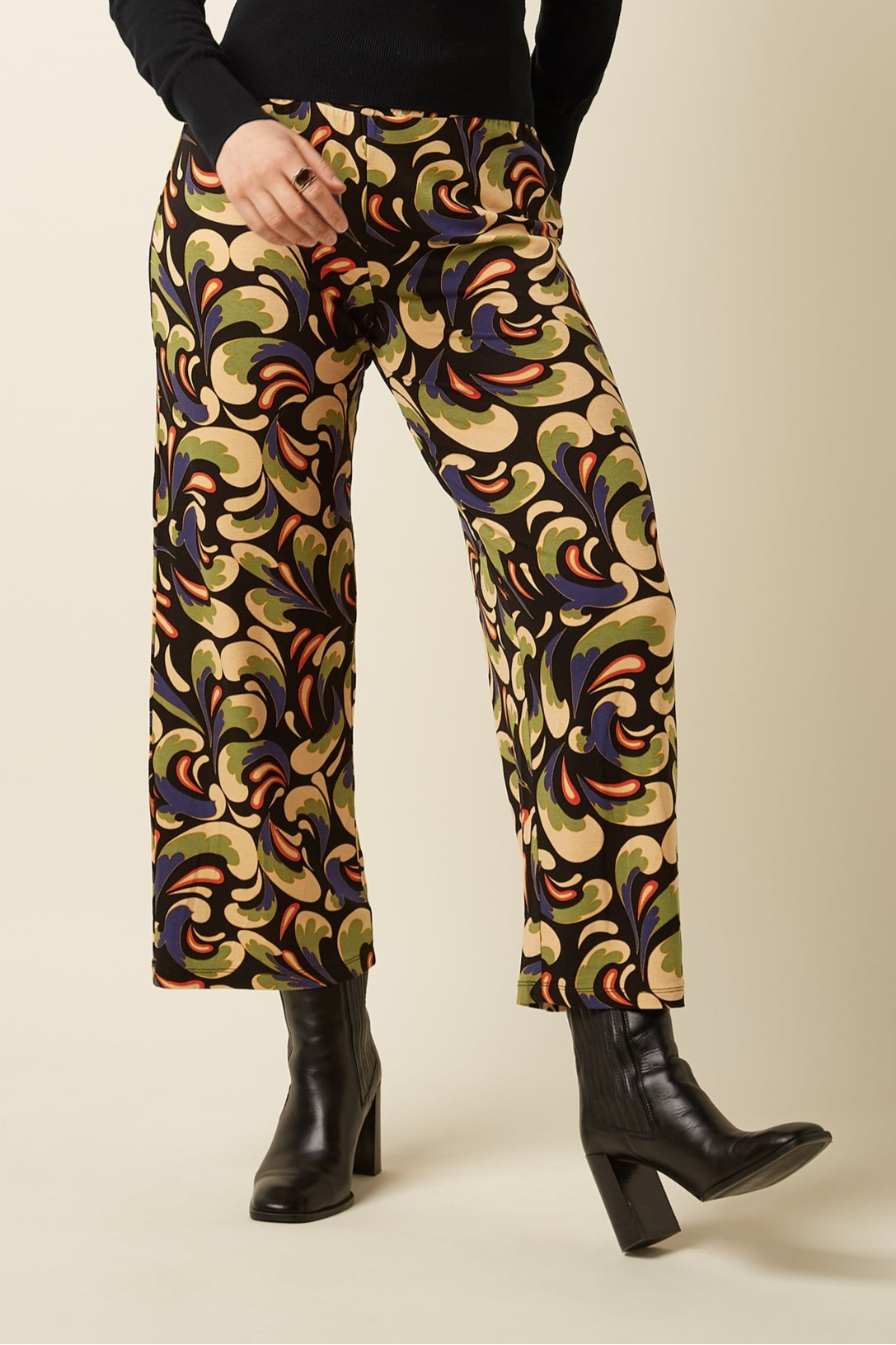 Colorful patterned pants worn with black boots on a beige background