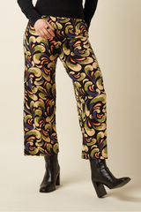 Colorful patterned pants worn with black boots on a beige background